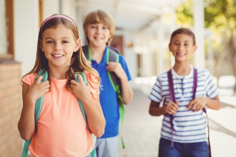 Smiling school kids standing in school corridor