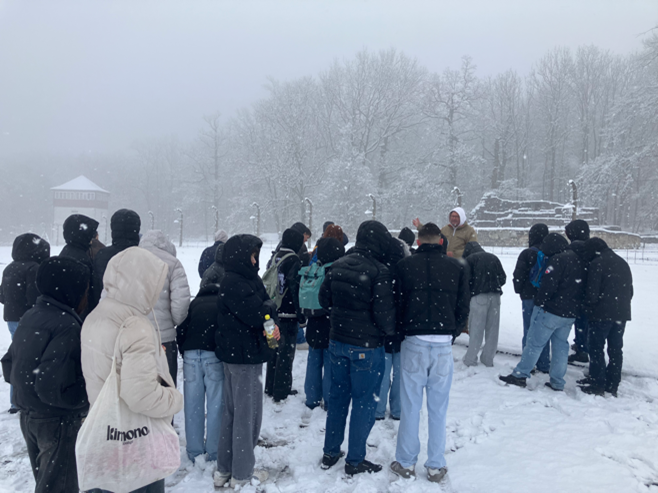 Eine Gruppe Menschen steht in dunkler Winterkleidung im verschneiten Park zusammen